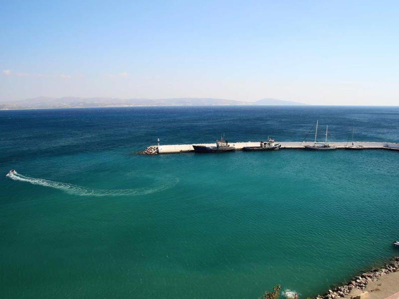Vista di un molo di porto marittimo con una barca che lascia una scia nell'acqua turchese.