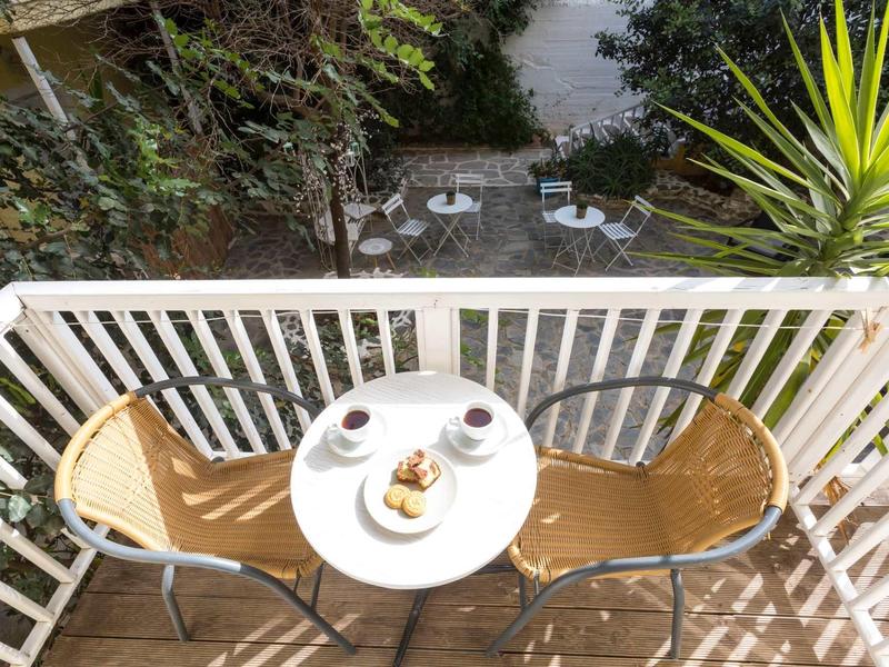 Balcone con tavolo, due sedie, caffè e snack con vista su giardino e terrazza.