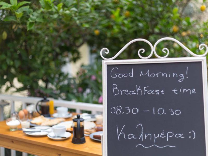 Lavagna che annuncia l'orario della colazione davanti a un tavolo da giardino apparecchiato.
