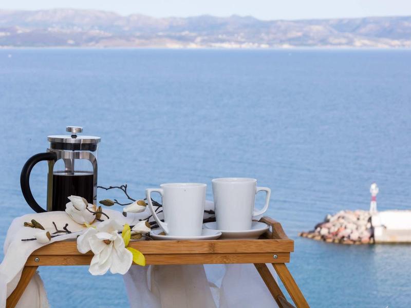 Caffettiera francese, due tazze e fiori su un vassoio con vista mare.