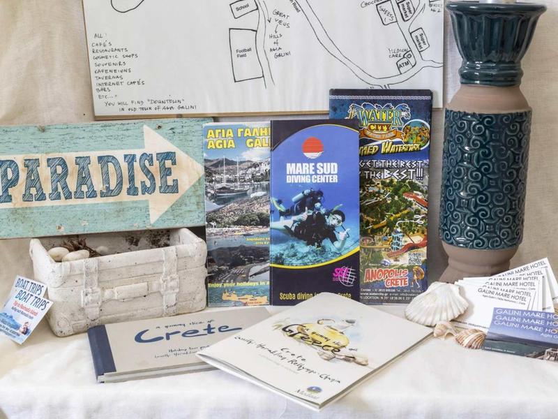 Tavolo decorativo con guide turistiche, brochure e souvenir, tra cui un vaso e un cartello Paradise.