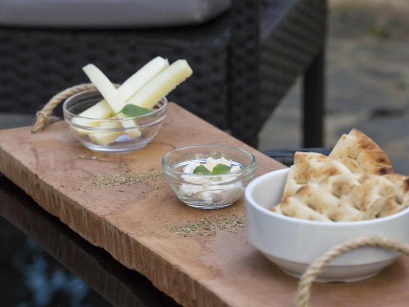 Tre ciotole piccole con snack su una tavola di legno rustica accanto a una sedia.