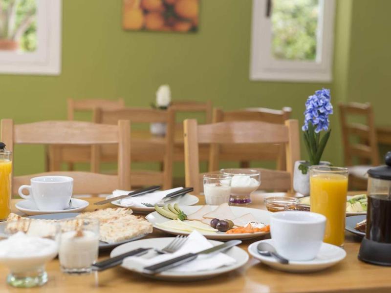 Tavolo per la colazione accogliente con succo d'arancia, caffè e paste in una stanza luminosa.