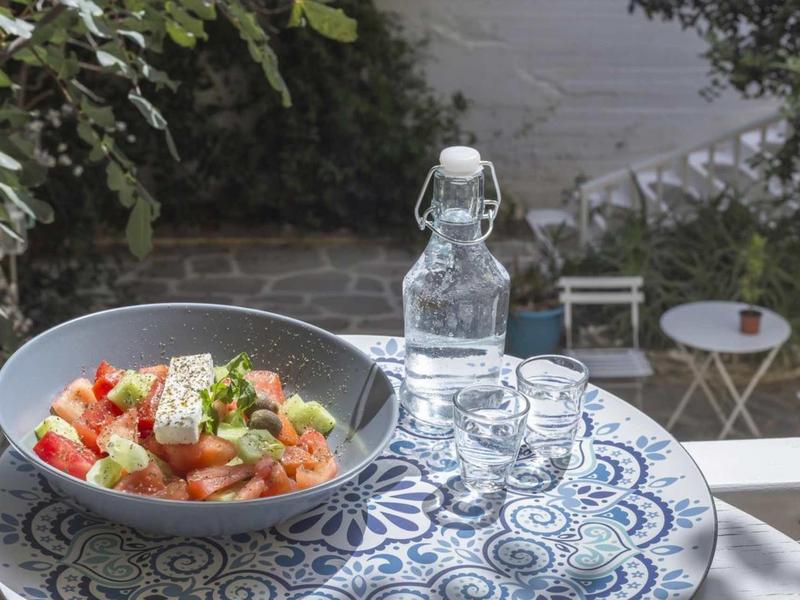 Ciotola con insalata e caraffa d'acqua su tavolo esterno decorato blu e bianco.