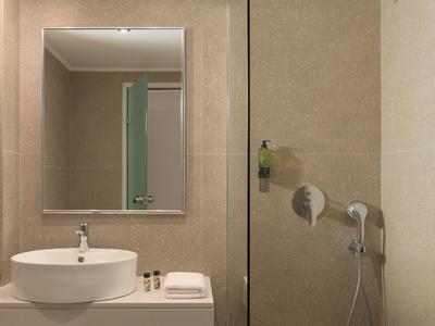 Bagno minimalista con lavabo rotondo, specchio e doccetta a parete.