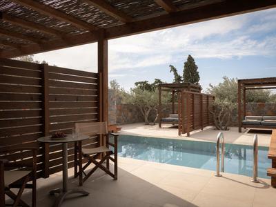Terrazza ombreggiata con tavoli, sedie e piscina all'aperto circondata dalla natura.