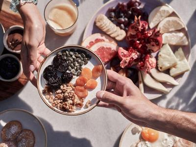 Un tavolo apparecchiato con muesli, frutta e varie creme spalmabili alla luce naturale.