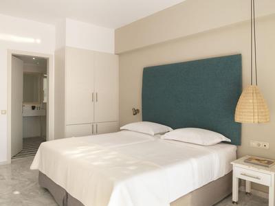Camera d'hotel luminosa con letto matrimoniale, testiera blu e bagno moderno.