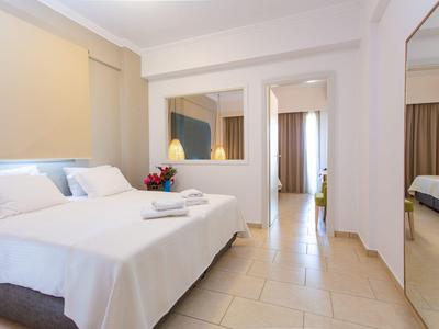 Camera d'hotel moderna con letto matrimoniale, pavimento piastrellato beige e grande specchio.