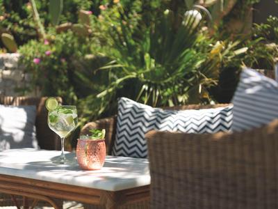 Terrazza con bevande fresche e cuscini decorativi su mobili da esterno.