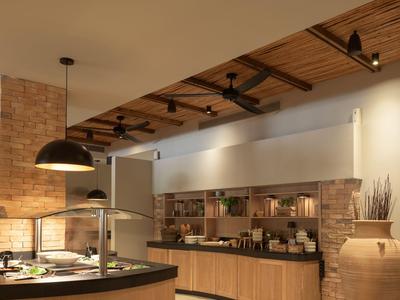 Area buffet moderna con soffitto in legno, parete in mattoni e postazioni cibo illuminate.