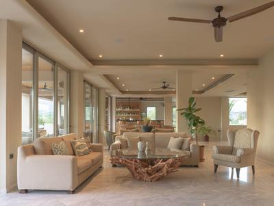 Soggiorno luminoso con divani beige, poltrone e tavolino in legno naturale, arredamento moderno.