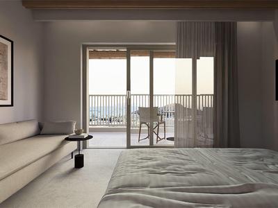 Camera d'hotel moderna con letto grande, divano, TV e balcone con vista mare.