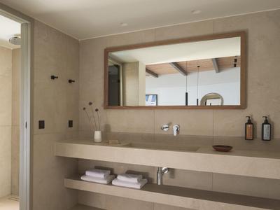 Bagno moderno con grande specchio, doppi lavandini e scaffali aperti con asciugamani.