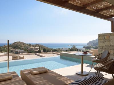 Piscina esterna moderna con vista sul mare, circondata da posti a sedere lounge e architettura in pietra naturale.