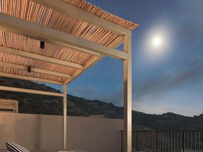 Terrazza coperta con area salotto di notte con vista su montagne e cielo stellato.