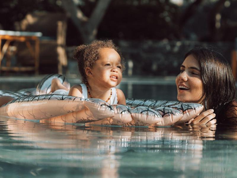 Una donna e un bambino nuotano in una piscina all'aperto con luce soffusa.