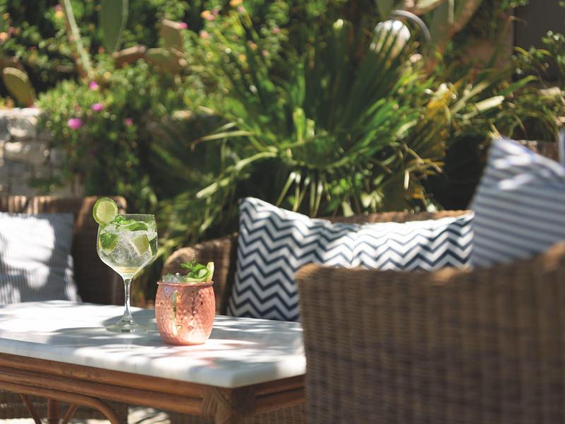 Terrazza con bevande fresche e cuscini decorativi su mobili da esterno.