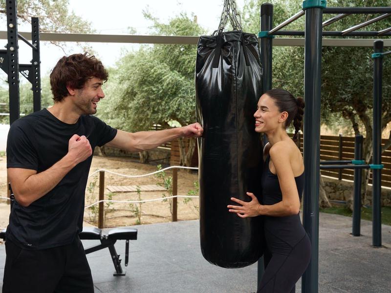 Due persone si allenano con un sacco da boxe in palestra all'aperto.