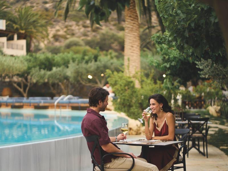 Coppia seduta vicino alla piscina che si gode bevande in un'atmosfera rilassata del resort.