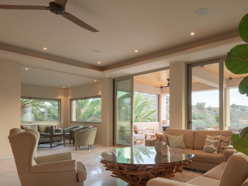 Soggiorno luminoso con divano beige, tavolo in legno naturale e vista verde esterna.