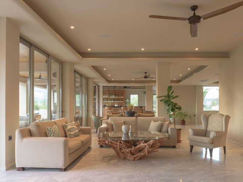 Soggiorno luminoso con divani beige, poltrone e tavolino in legno naturale, arredamento moderno.