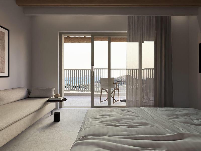 Camera d'hotel moderna con letto grande, divano, TV e balcone con vista mare.