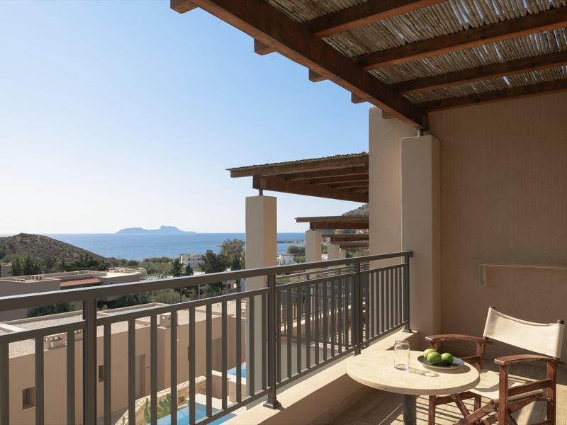 Balcone con tavolo e sedia con vista sul mare e le montagne in lontananza.