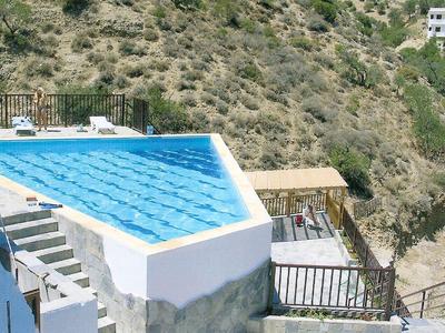 Basen z widokiem na pagórkowaty krajobraz i białe budynki w słoneczny dzień