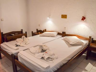 A simple hotel room with two single beds, white sheets, and wooden frames.