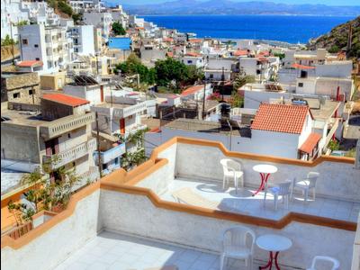 Blick auf eine bergige Küstenstadt mit Terrassenrestaurants und blauem Meer im Hintergrund.