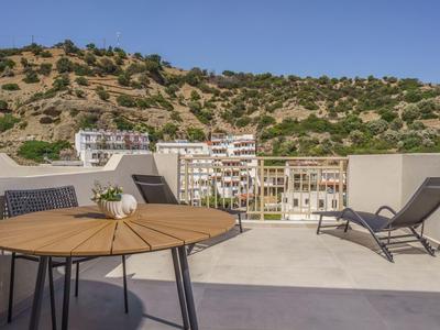 Terrasse mit modernem Möbelset und Blick auf grüne Hügel und Wohngebäude.