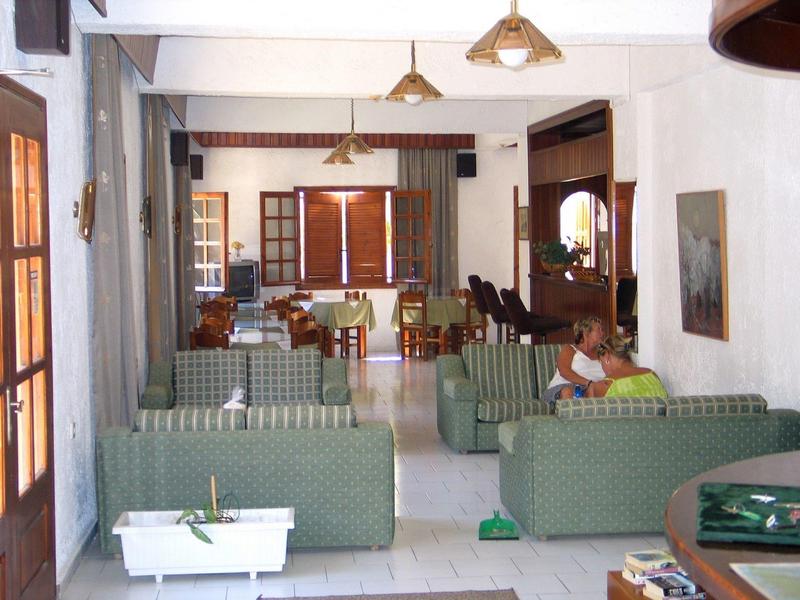 Jasny salon z zielonymi sofami, drewnianym stołem i krzesłami w hotelu lub domu wakacyjnym.