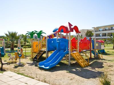 Bunter Spielplatz mit Rutschen und Klettergerüst auf sandigem Boden bei sonnigem Wetter.