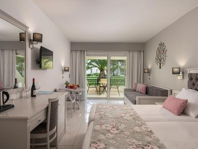 Modernes Hotelzimmer mit Doppelbett, Schreibtisch und Terrasse mit Blick auf Garten.