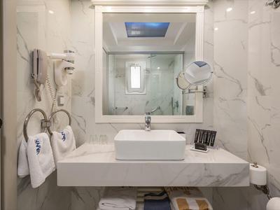 Modernes Badezimmer mit Waschbecken, großem Spiegel und Marmorwaschtisch.