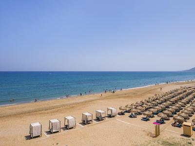 Strand mit Reihen von Strandkörben und Sonnenschirmen, blauer Himmel und Meer im Hintergrund.