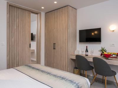 Nowoczesny pokój hotelowy z drewnianymi meblami, biurkiem, krzesłami i telewizorem ściennym.