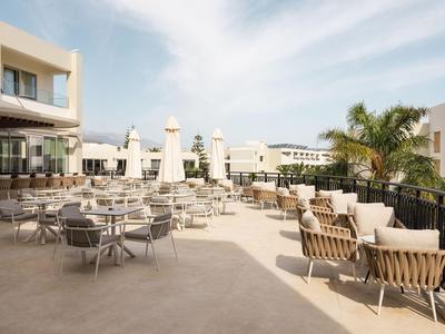 Jasny taras hotelowy z nowoczesnymi miejscami do siedzenia i palmami pod czystym niebem.
