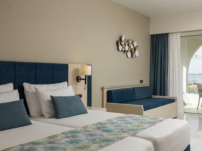 Nowoczesny pokój hotelowy z podwójnym łóżkiem, ławką i tarasem z widokiem na morze.