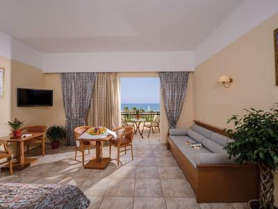 Heller Wohnraum mit Tisch, Stühlen, Sofa, Balkon und Meerblick bei Tageslicht.