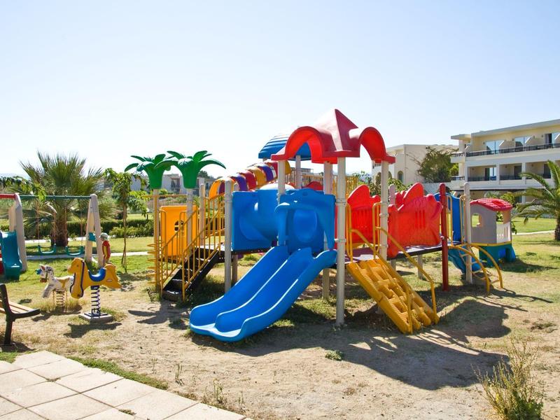 Bunter Spielplatz mit Rutschen und Klettergerüst auf sandigem Boden bei sonnigem Wetter.
