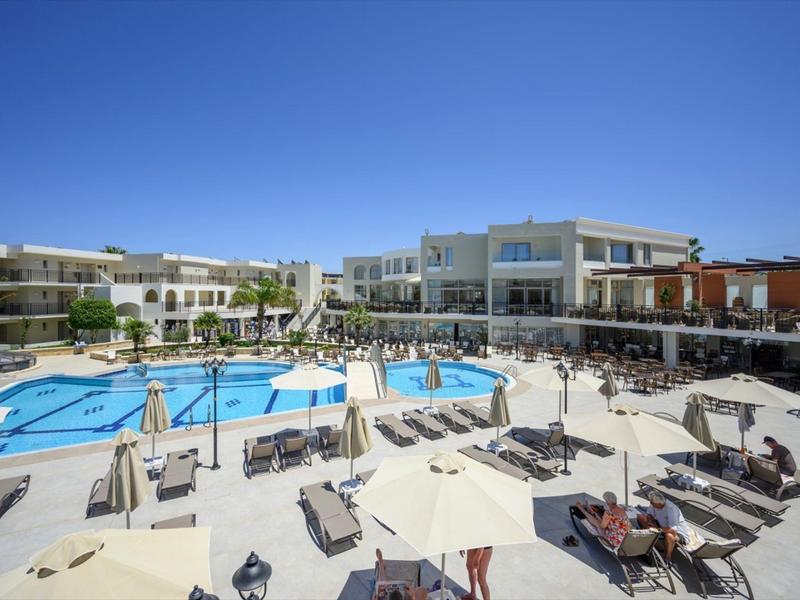 Großer Hotelkomplex mit blauem Pool, Liegestühlen und Sonnenschirmen bei klarem Himmel.