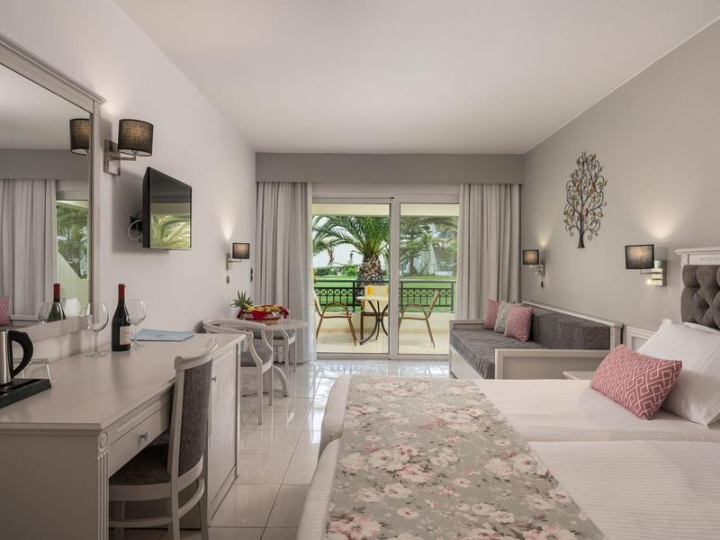 Modernes Hotelzimmer mit Doppelbett, Schreibtisch und Terrasse mit Blick auf Garten.