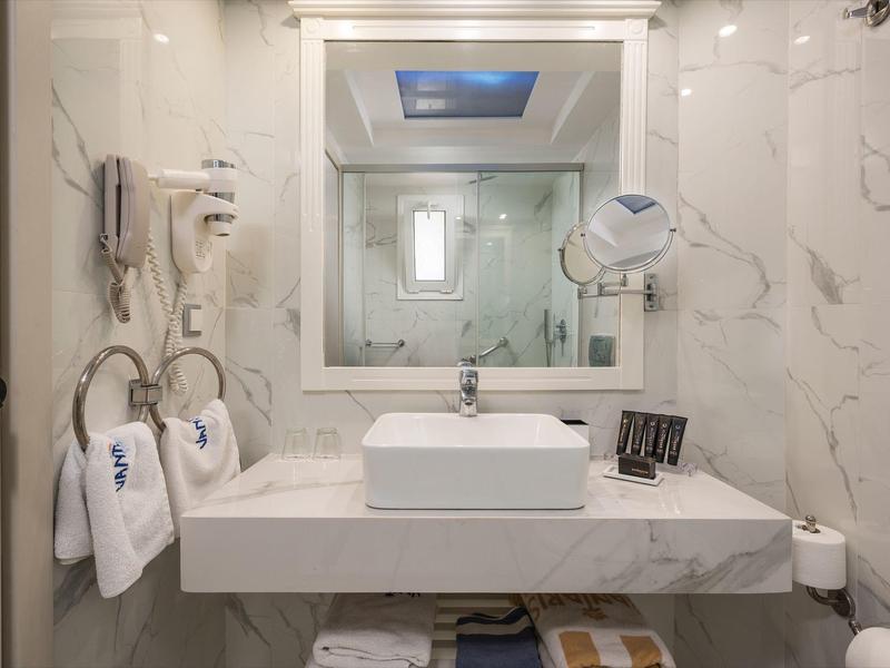 Modernes Badezimmer mit Waschbecken, großem Spiegel und Marmorwaschtisch.