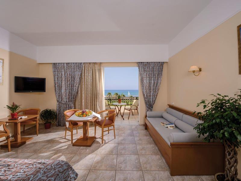 Heller Wohnraum mit Tisch, Stühlen, Sofa, Balkon und Meerblick bei Tageslicht.