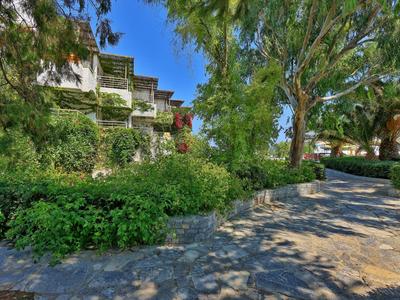 Hotel s balkony obklopený stromy a dlážděnou cestou v popředí