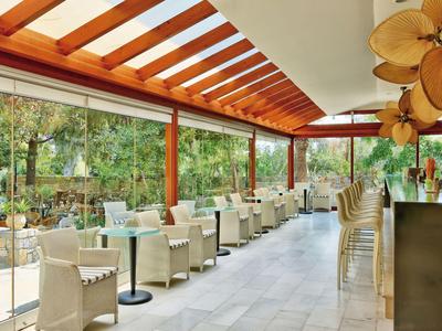 Veranda luminosa e moderna con sedie bianche e grandi finestre con vista sul verde.