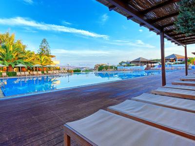 Grande piscina con lettini prendisole con vista su palme e cielo azzurro in un resort.