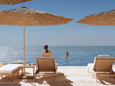 Lettini da spiaggia con ombrelloni presso il mare calmo e una persona che nuota in acqua.